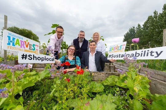 People with signs behind vegetable plot